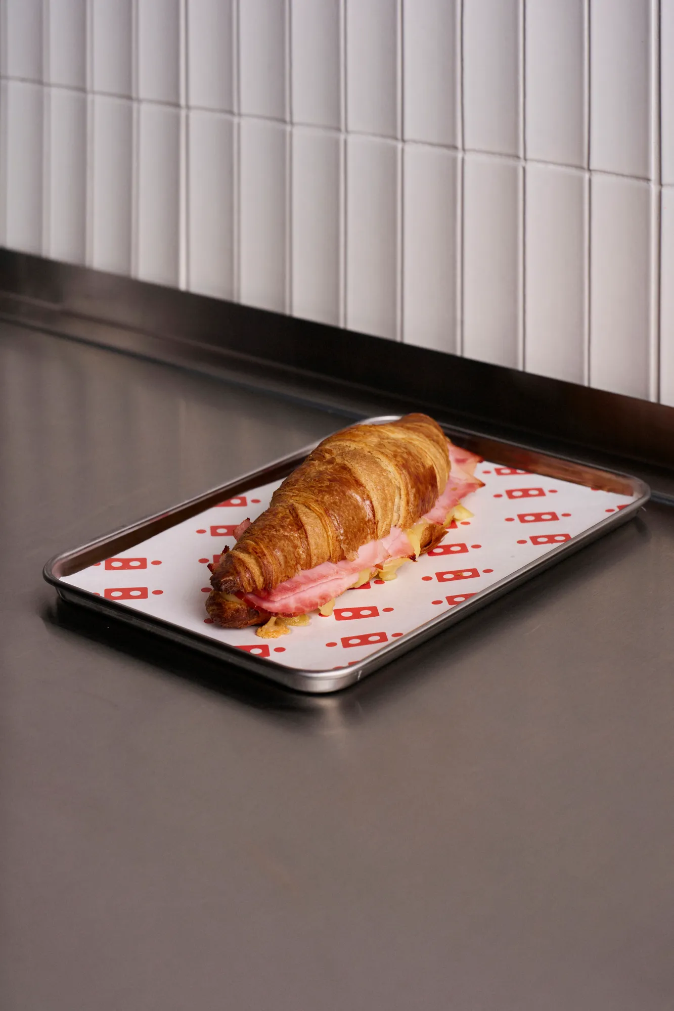Sandwich de prosciutto en croissant sobre una bandeja Café Tape